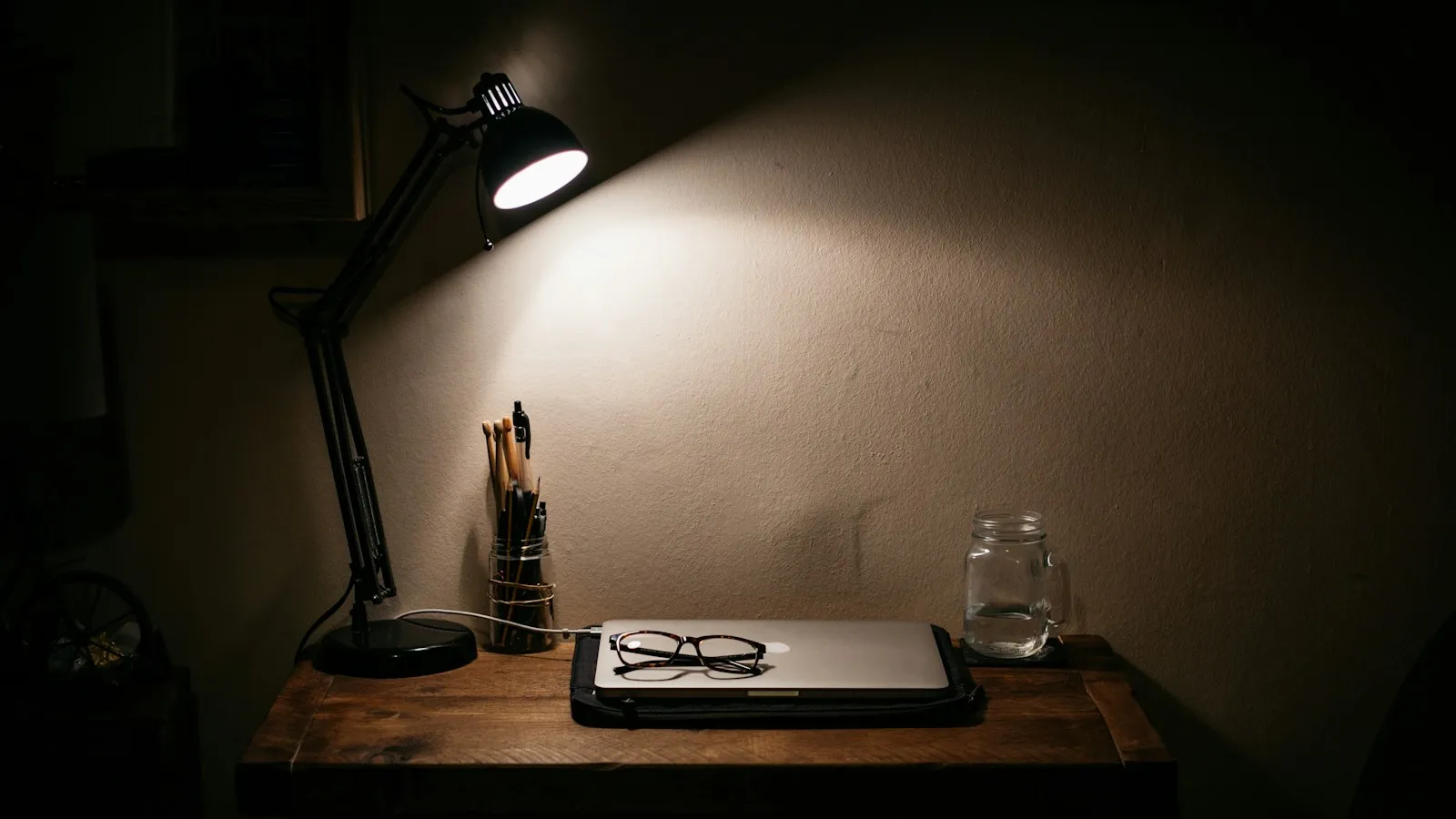 Bureau de travail éclairé par une lampe, carnet et stylo posés